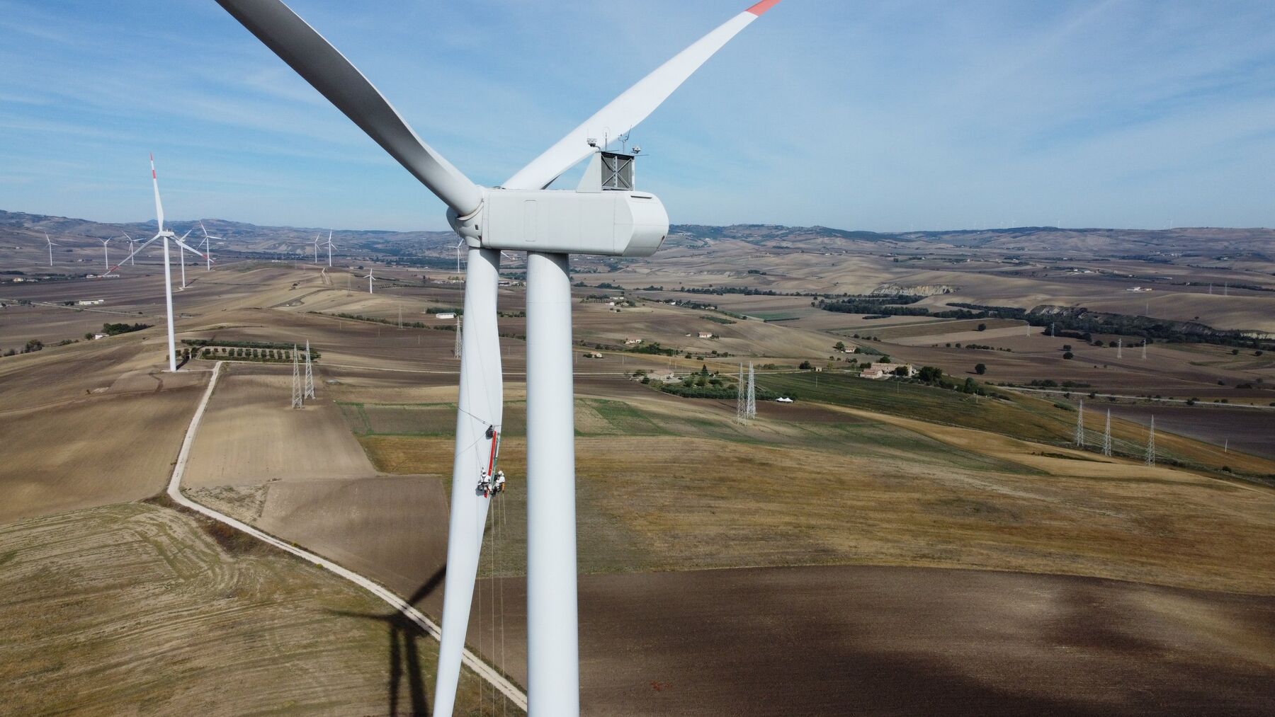 Wind turbine with rope access technicians working on a blade